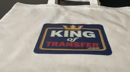 Sac tote bag en tissu blanc avec un marquage coloré au centre portant le logo « King of Transfer », comprenant une couronne et un encadrement bleu.